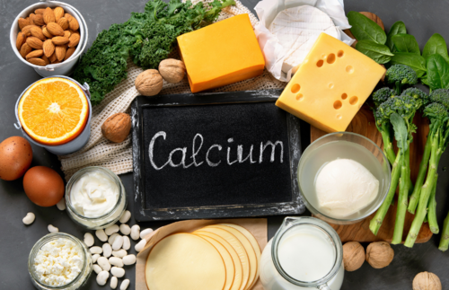 Schild mit Aufschrift Calcium liegt umgeben von Käse, Nüssen und Eiern