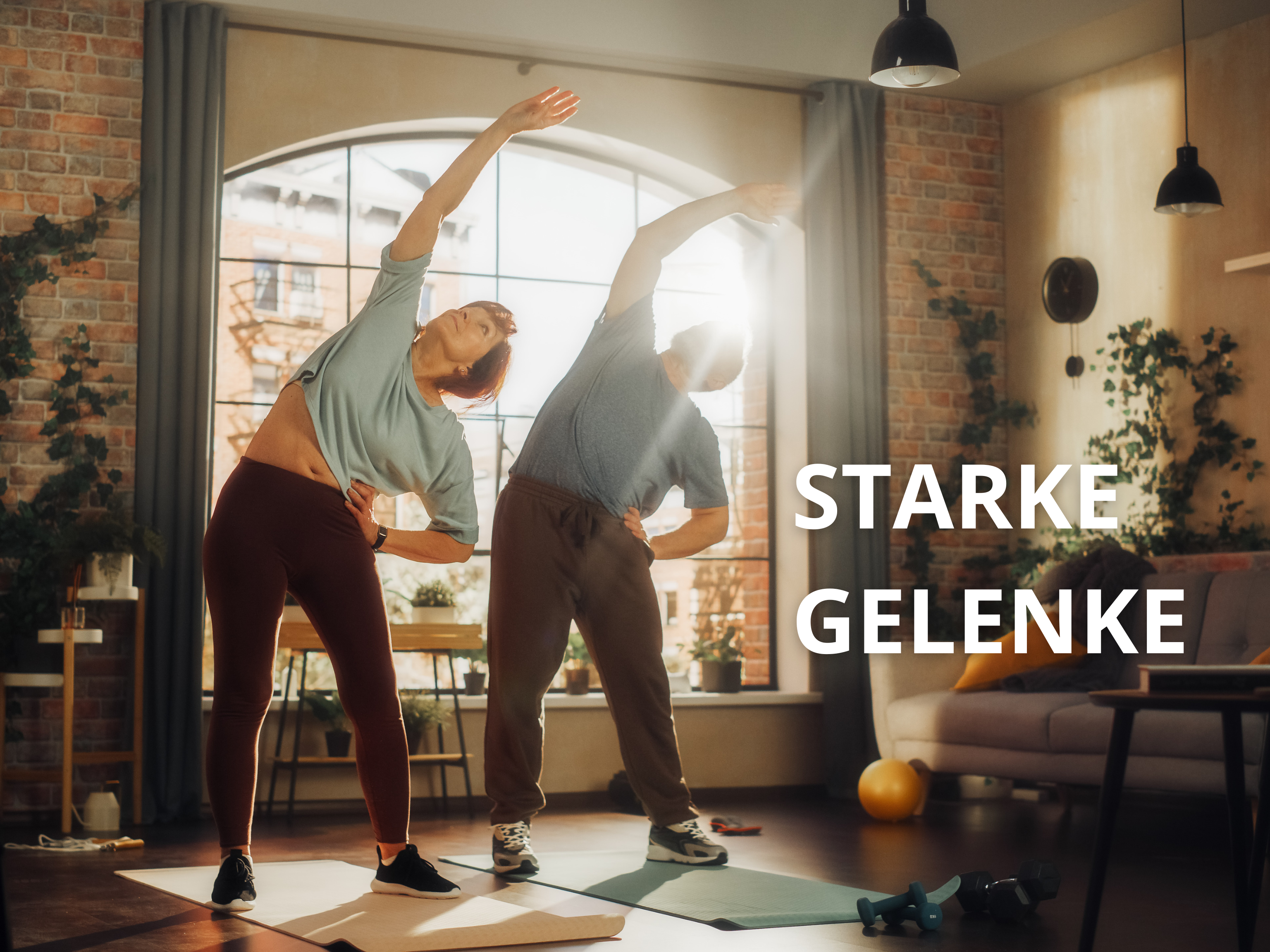 Ein Mann (rechts) und eine Frau (links) dehnen sich wobei sie den rechten Arm nach oben Strecken und dabei auf einer Yoga-Matte stehen.
