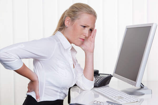 Frau mit Rückenschmerzen am Arbeitsplatz