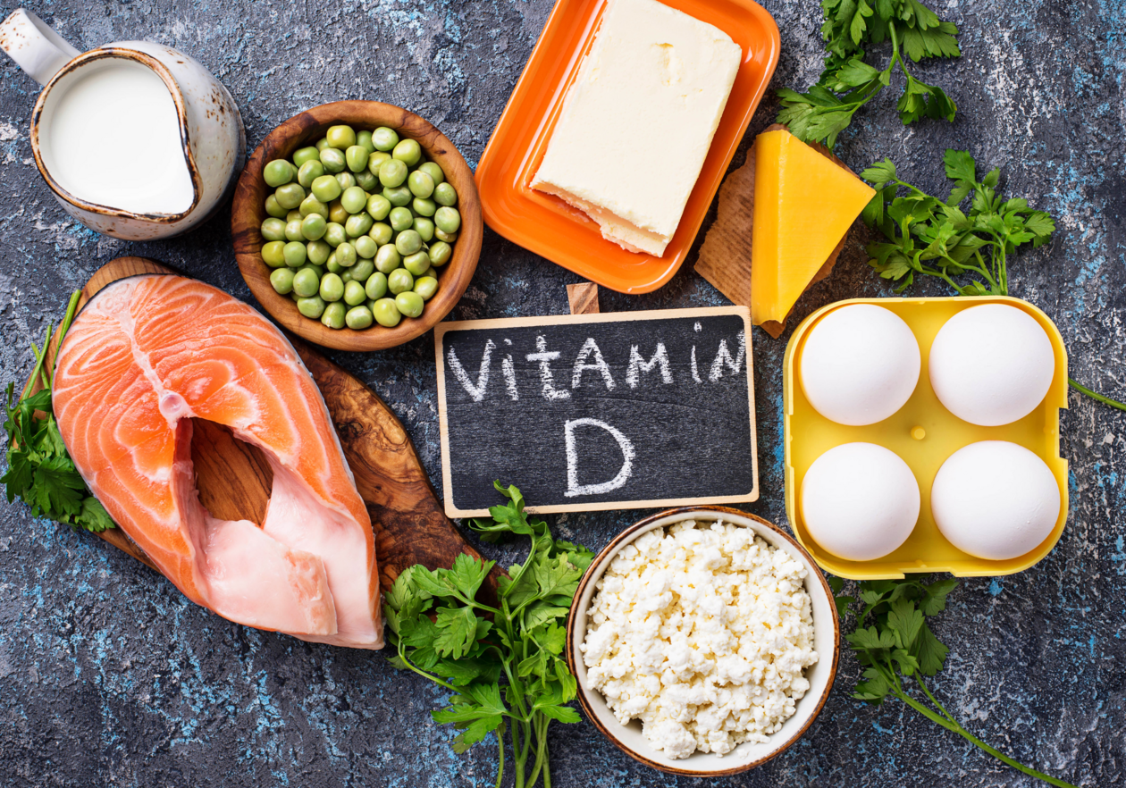 Schild mit Aufschrift Vitamin D liegt umgeben von Fisch, Milchprodukten und Eiern