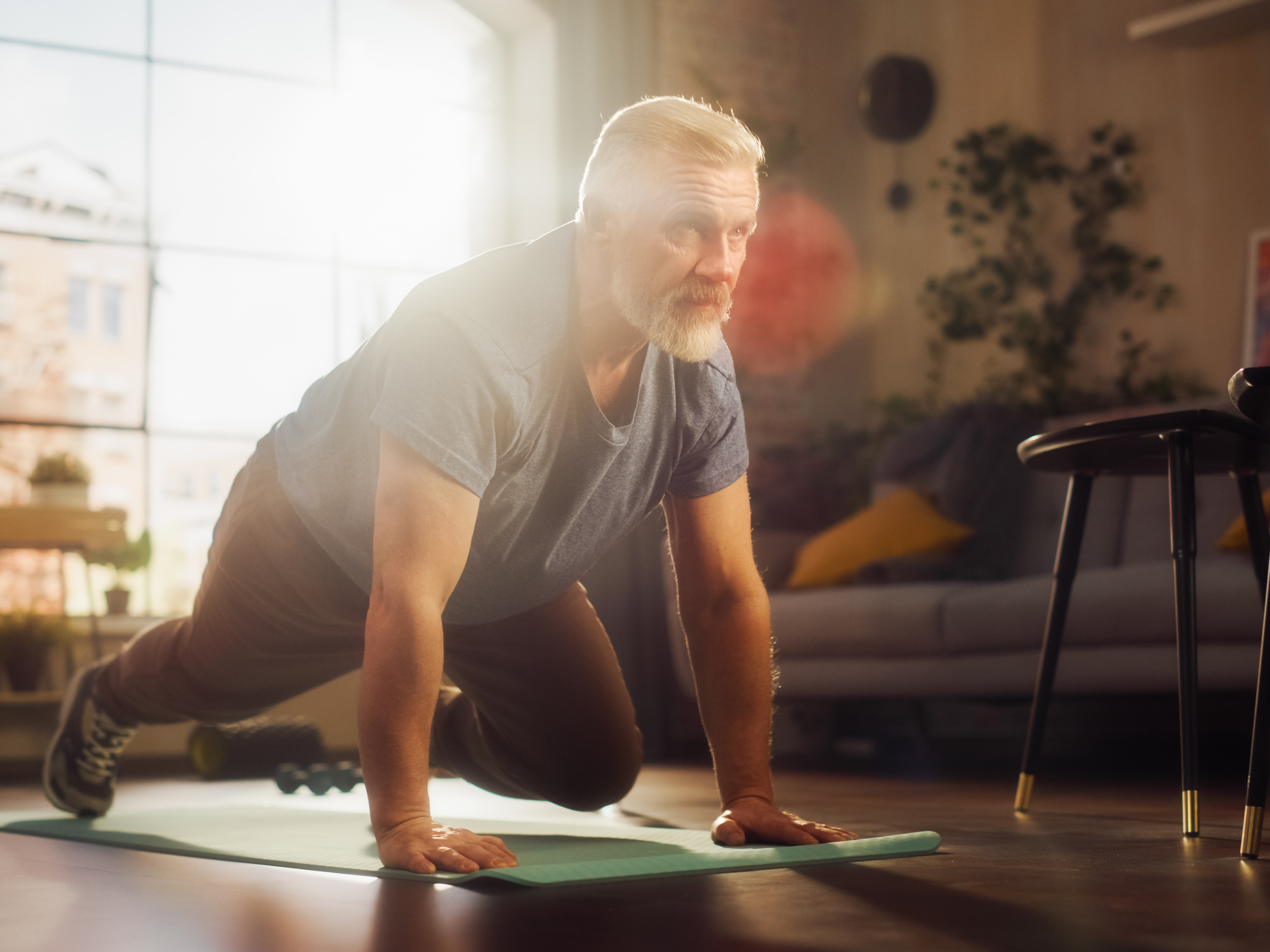 Ein Mann (mittig) macht Liegestütz auf einer grünen Fitnessmatte.