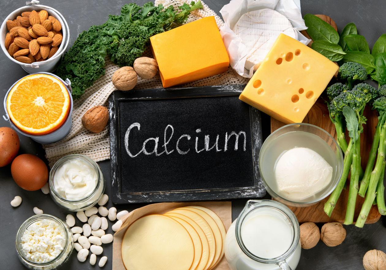 Schild mit Aufschrift Calcium liegt umgeben von Käse, Nüssen und Eiern